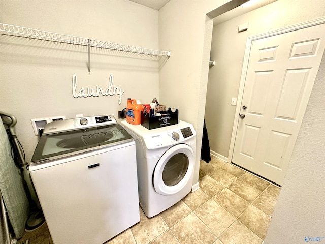 washroom featuring laundry area, washer and clothes dryer, baseboards, and light tile patterned floors