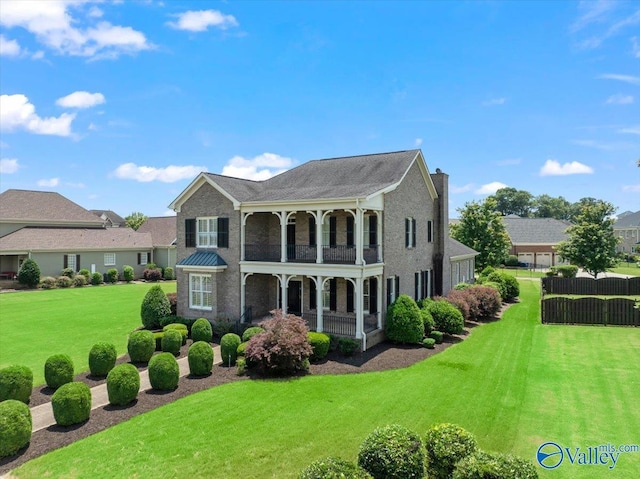 exterior space featuring a balcony, a front yard, and covered porch