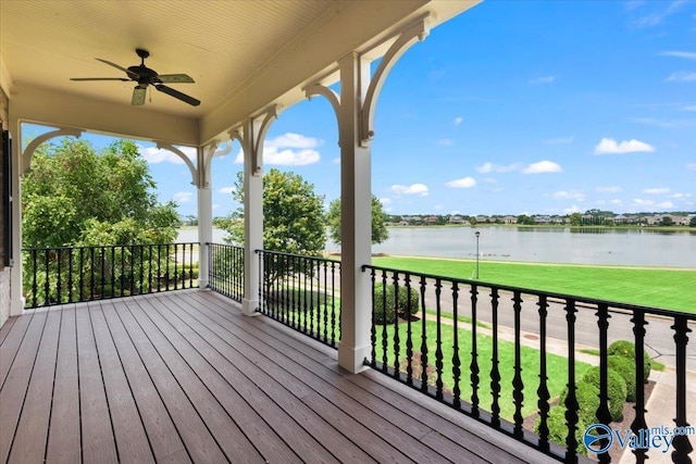 wooden terrace featuring a water view, ceiling fan, and a lawn