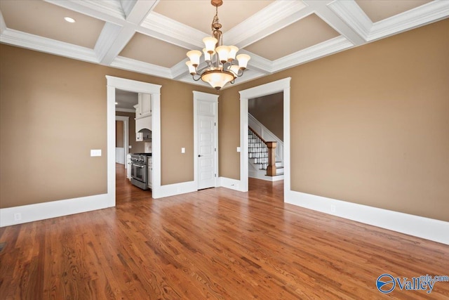 unfurnished dining area featuring beamed ceiling, wood-type flooring, coffered ceiling, and a notable chandelier