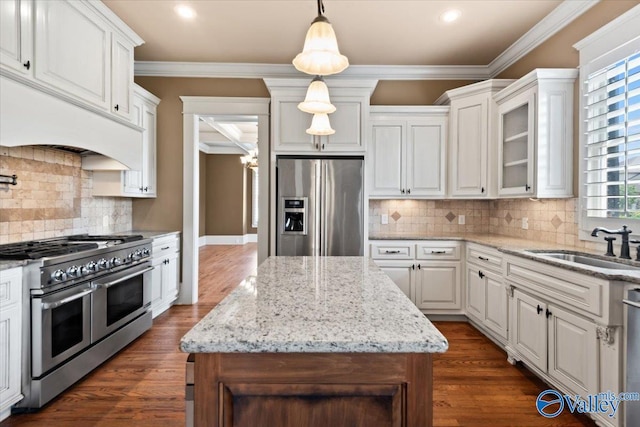 kitchen featuring crown molding, hanging light fixtures, a kitchen island, stainless steel appliances, and white cabinets