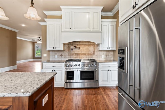 kitchen with pendant lighting, white cabinets, crown molding, and premium appliances