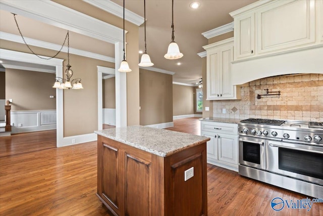 kitchen featuring dark hardwood / wood-style floors, hanging light fixtures, double oven range, crown molding, and light stone countertops