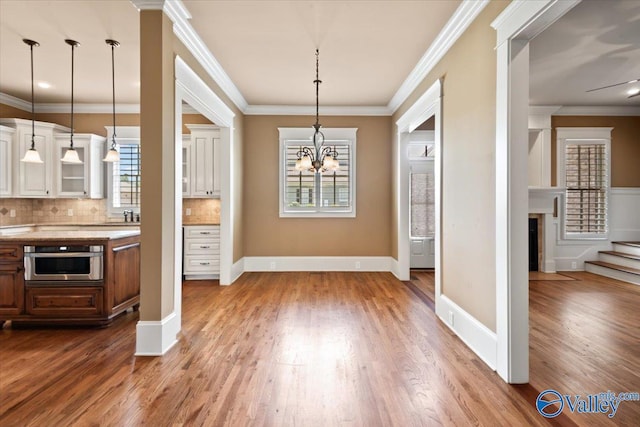 kitchen featuring decorative backsplash, stainless steel oven, hanging light fixtures, and white cabinets