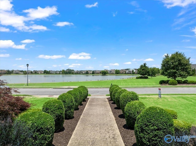 surrounding community with a water view and a yard