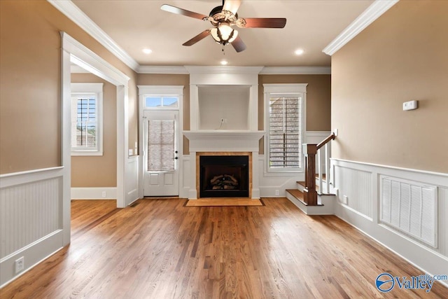 unfurnished living room featuring hardwood / wood-style floors, ornamental molding, and ceiling fan