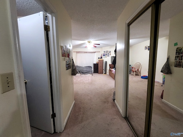 corridor featuring light carpet and a textured ceiling