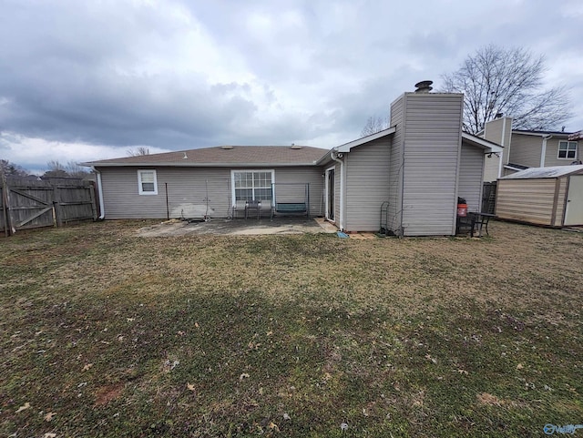 back of house with a lawn, a patio, and a storage unit