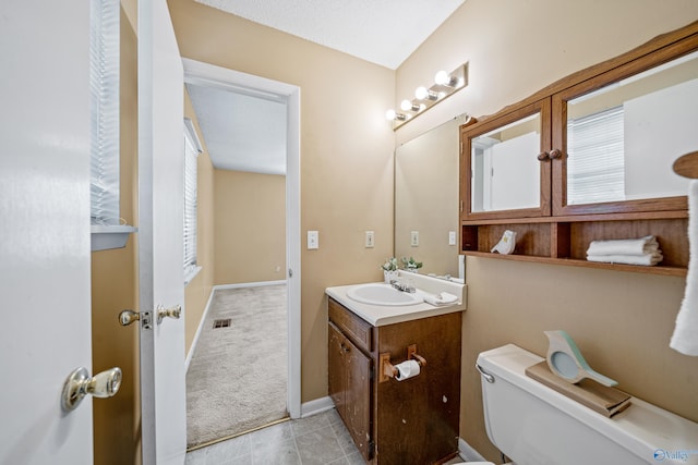 bathroom featuring tile patterned flooring, toilet, visible vents, vanity, and baseboards