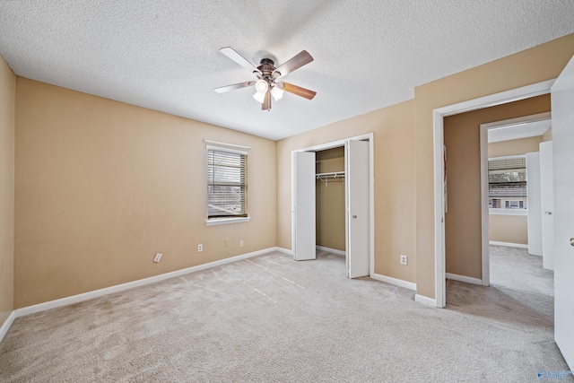 unfurnished bedroom with carpet floors, a closet, ceiling fan, a textured ceiling, and baseboards