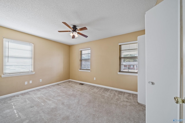 empty room featuring a ceiling fan, a healthy amount of sunlight, a textured ceiling, and carpet flooring