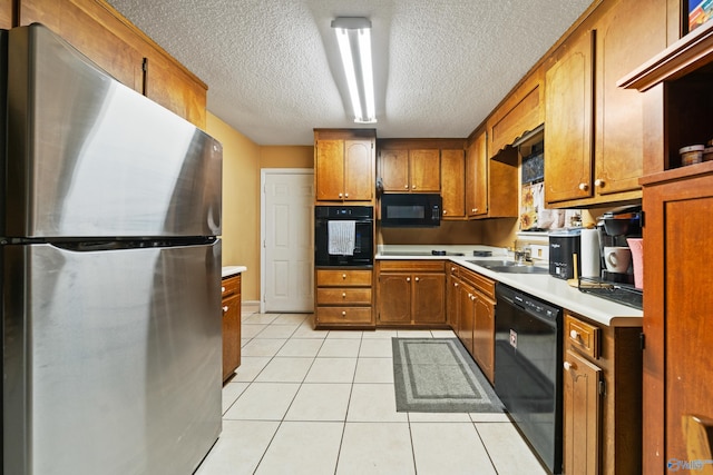 kitchen featuring light tile patterned flooring, sink, a textured ceiling, and black appliances