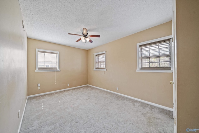 spare room with ceiling fan, a textured ceiling, carpet, and baseboards