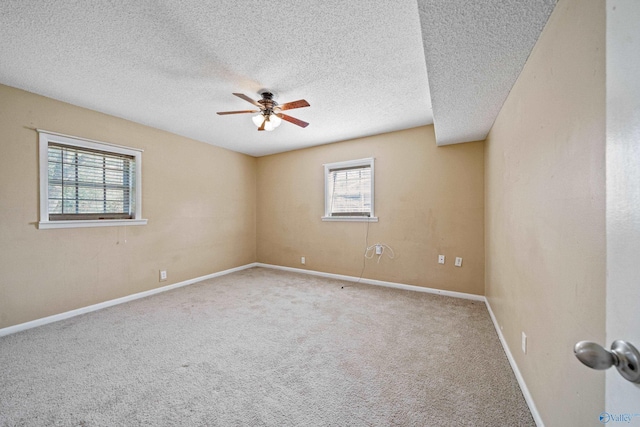 spare room with a textured ceiling, carpet, a ceiling fan, and baseboards