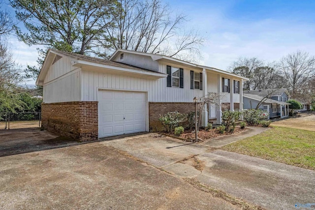 view of front facade with driveway, fence, and brick siding