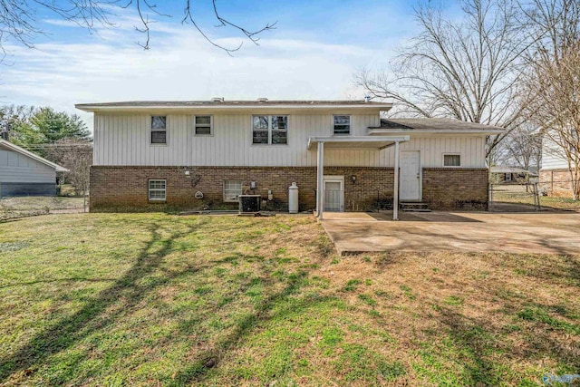 back of house with a lawn, fence, central air condition unit, a patio area, and brick siding