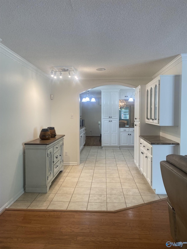 1702 Roseberry Dr, Scottsboro, AL 35769 - interior space featuring a textured ceiling, crown molding, dark countertops, arched walkways, and light wood finished floors