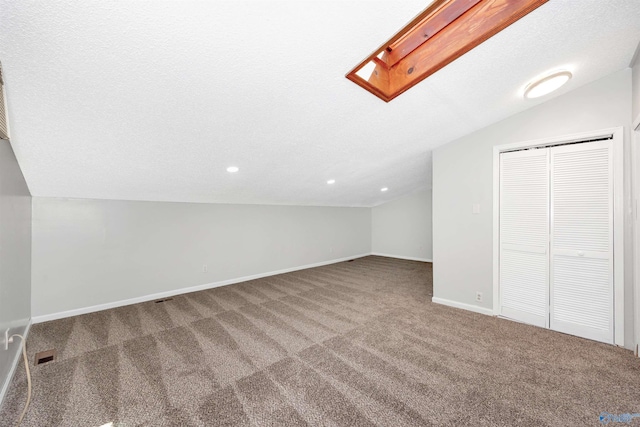 409 Hobbs Rd SE, Huntsville, AL 35803 - bonus room featuring a textured ceiling, visible vents, baseboards, carpet, and vaulted ceiling with skylight