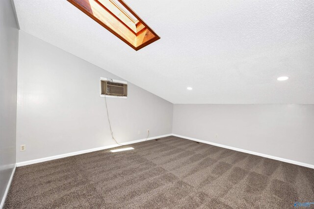 409 Hobbs Rd SE, Huntsville, AL 35803 - additional living space featuring a wall mounted air conditioner, vaulted ceiling with skylight, baseboards, dark colored carpet, and recessed lighting
