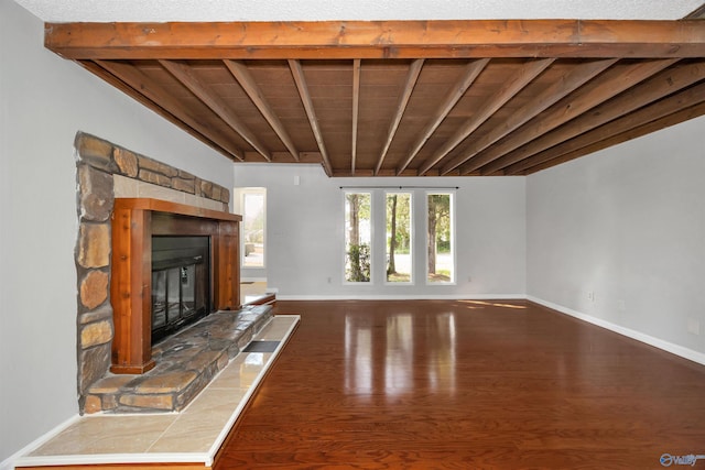 409 Hobbs Rd SE, Huntsville, AL 35803 - unfurnished living room with beamed ceiling, wood finished floors, baseboards, and a stone fireplace