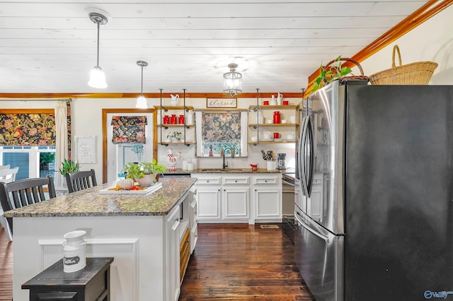 kitchen with decorative light fixtures, white cabinetry, stainless steel refrigerator, dark hardwood / wood-style floors, and dark stone countertops