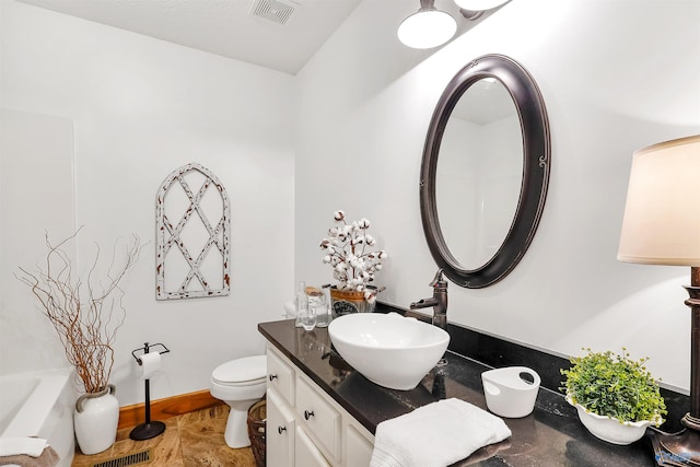 bathroom featuring vanity, toilet, and a washtub