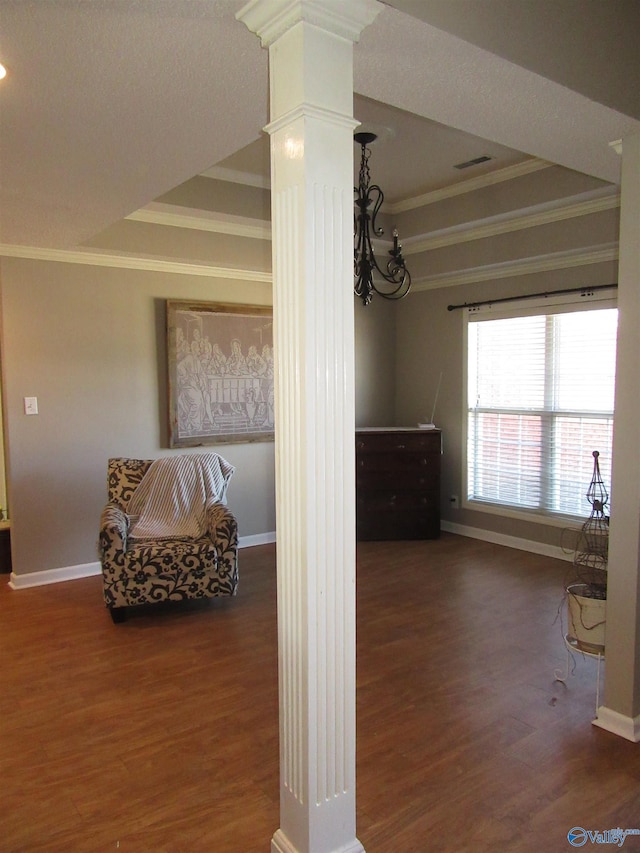 interior space with ornamental molding, a raised ceiling, ornate columns, and wood finished floors