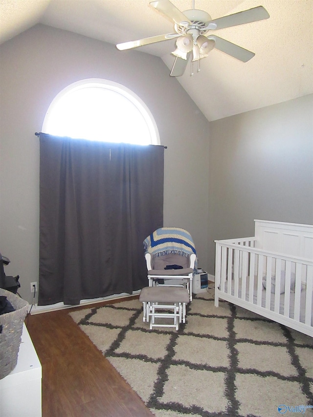 bedroom featuring lofted ceiling, ceiling fan, a nursery area, and wood finished floors