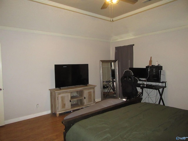 bedroom with baseboards, a raised ceiling, a ceiling fan, wood finished floors, and crown molding