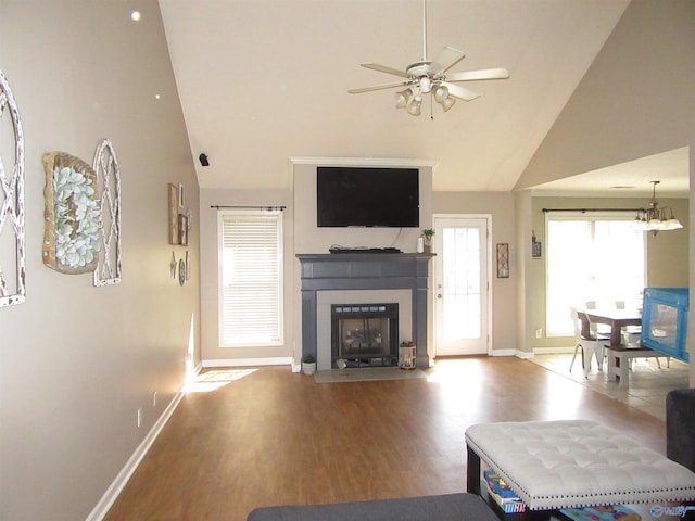 living room featuring a fireplace with flush hearth, ceiling fan, wood finished floors, high vaulted ceiling, and baseboards