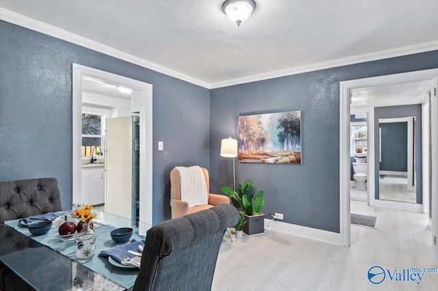 dining room with baseboards, visible vents, a textured wall, wood finished floors, and crown molding