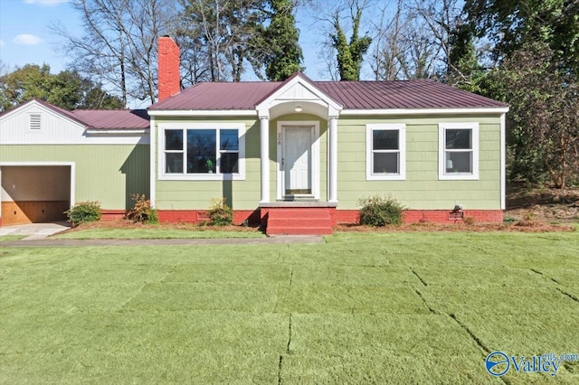 view of front of home featuring an attached garage, metal roof, a chimney, and a front lawn