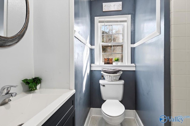 bathroom with baseboards, vanity, and toilet