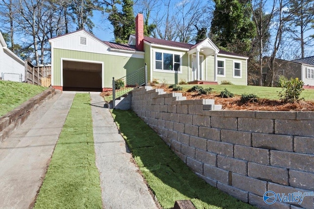 ranch-style home featuring a front yard, concrete driveway, metal roof, and a chimney