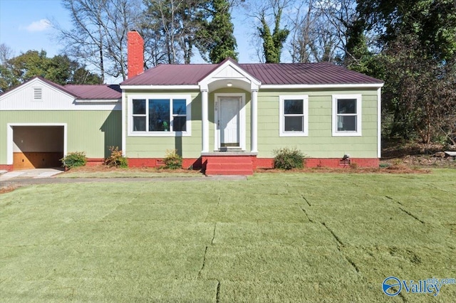 view of front of property with a garage, metal roof, a chimney, and a front lawn