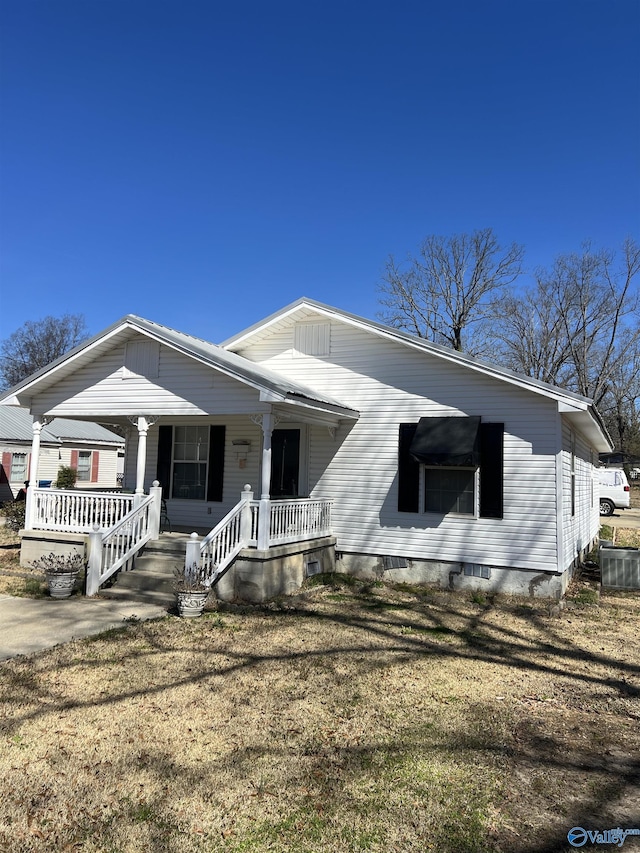 view of front facade with a front yard, covered porch, and crawl space