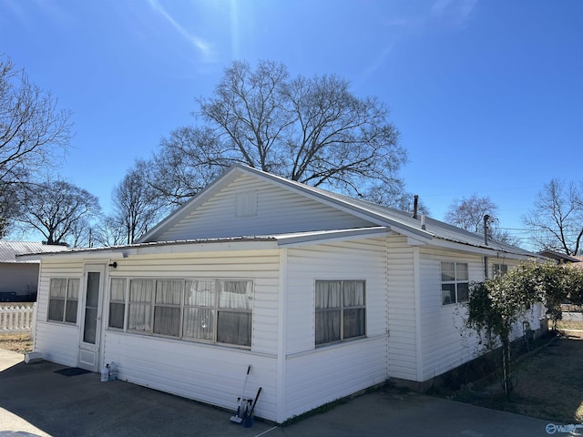 view of side of property featuring metal roof and fence