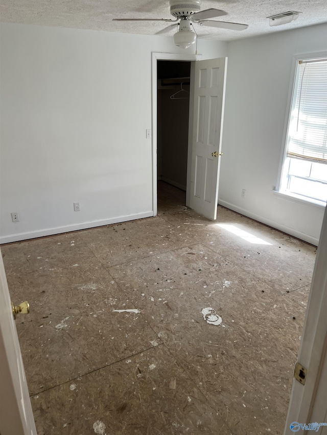 empty room featuring a textured ceiling, ceiling fan, and baseboards