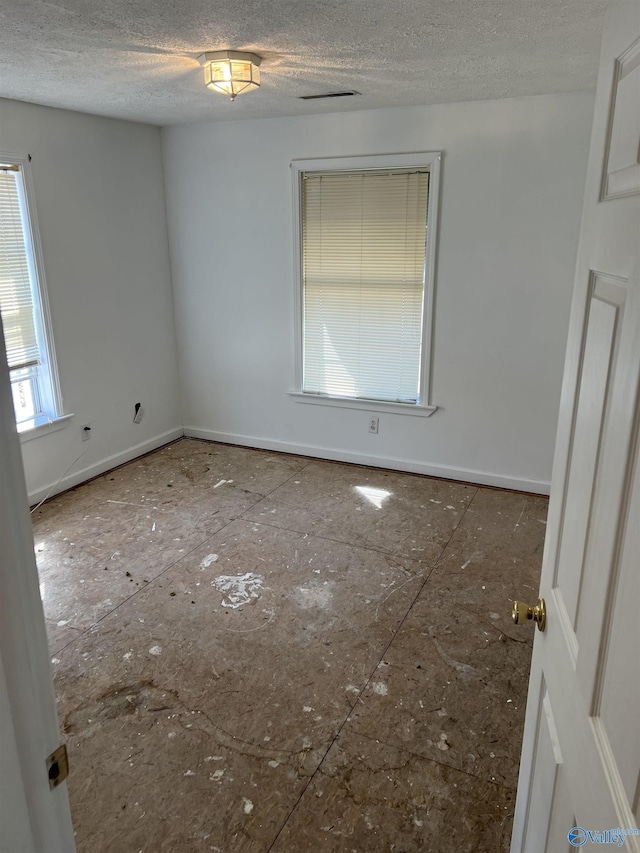 empty room with baseboards and a textured ceiling