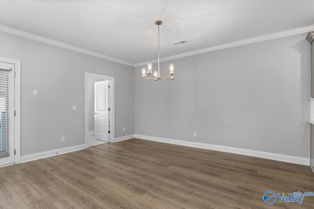 empty room featuring hardwood / wood-style floors, a chandelier, and ornamental molding