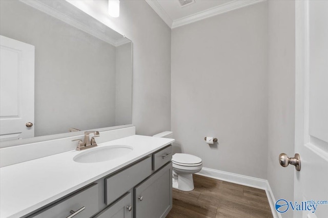 bathroom featuring wood-type flooring, vanity, toilet, and crown molding