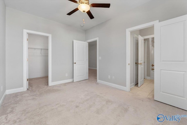 unfurnished bedroom featuring ceiling fan, light colored carpet, a spacious closet, and a closet