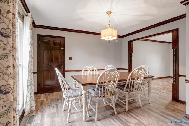 dining space with an inviting chandelier, crown molding, and light hardwood / wood-style floors