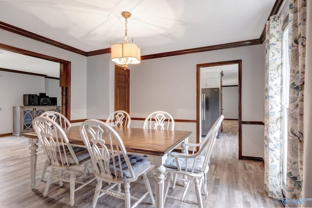 dining space with crown molding and light hardwood / wood-style flooring