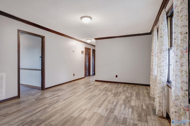 empty room featuring a textured ceiling, ornamental molding, and light wood-type flooring