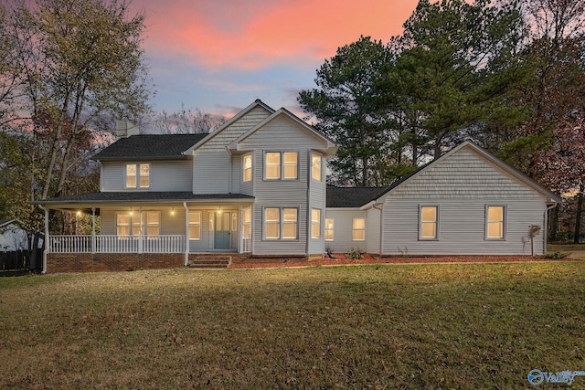 back house at dusk with a porch and a yard