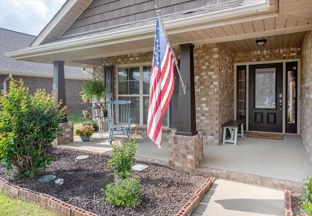 doorway to property with brick siding and covered porch