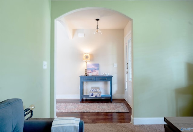living area featuring arched walkways, baseboards, and wood finished floors