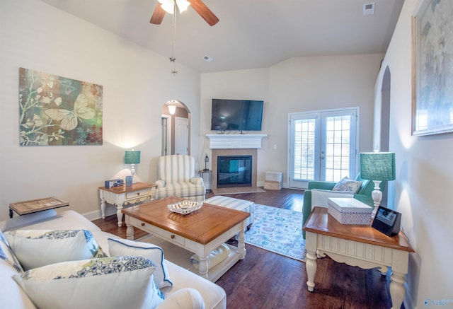 living area featuring ceiling fan, arched walkways, a fireplace with flush hearth, wood finished floors, and visible vents