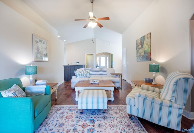 living area with arched walkways, a ceiling fan, baseboards, wood finished floors, and vaulted ceiling